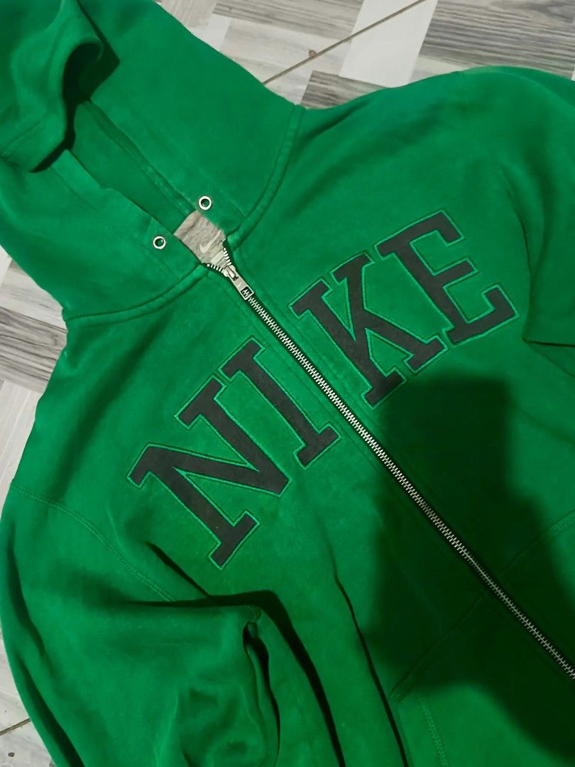 Nike Green Zip-Up Hoodie (Category: Coats, Jackets and Outerwear) located in Urdaneta. Submitted by goldeneagle-e662 (Listing ID 1464470098, Image 2). Description: - Green Nike hoodie - Full zip closure - Convenient pockets - Large "NIKE" graphic on the front - Small Nike swoosh on the sleeve - Comfortable and casual design - Ideal for everyday wear.