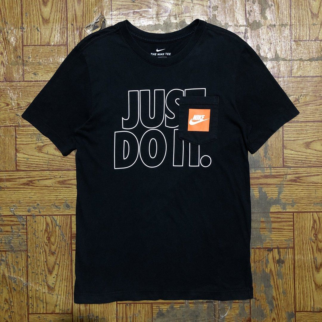 NIKE JDI POCKET TEE (Category: Tshirts & Polo Shirts ) located in Dasmarinas. Submitted by corenyxmessy_3rd_account (Listing ID 1464409645, Image 1). Description: This item is a Nike Men’s Sportswear JDI Graphic Pocket T-Shirt in black, featuring the classic hollowed-out “JUST DO IT.” typography paired with an orange Nike Futura logo printed directly onto the chest pocket. width - 17.5 length - 27.