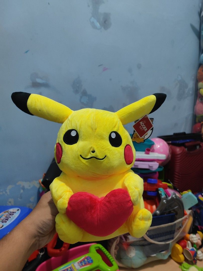 Pikachu Plush Toy Holding a Red Heart (Category: Plushies & Soft Toys) located in Iligan City. Submitted by sneakymagician (Listing ID 1464432139, Image 1). Description: - Adorable Pikachu plush toy - Comes with a cute red heart accessory - Perfect gift for any Pokemon enthusiast - Brand: AOGER - Soft, cuddly, and ready for a new loving home!.