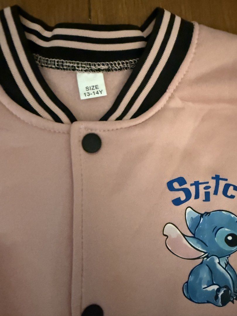 Pink Stitch Bomber Jacket (Category: Babies & Kids Fashion) located in Bulacan. Submitted by emjay_17 (Listing ID 1464386104, Image 2). Description: - Cute pink bomber jacket - Features Stitch graphic on front and back - Black sleeves with striped cuffs and collar - Snap button closure - Size: 13-14 Years.