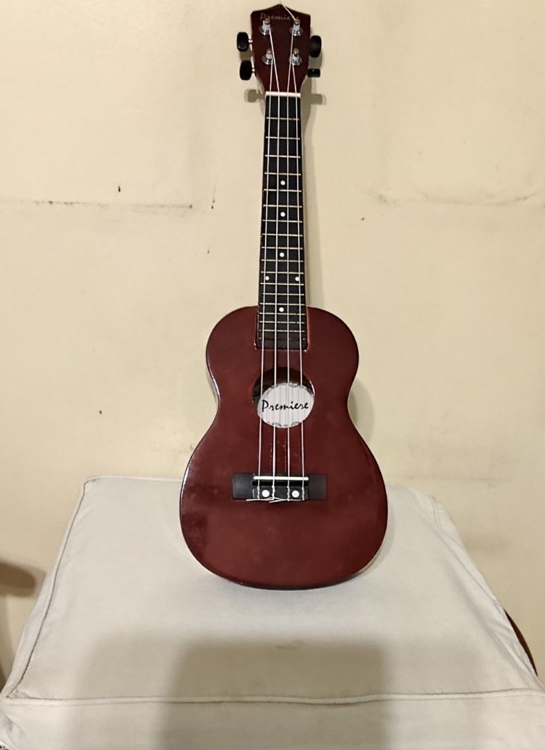 Premiere Ukulele with Gig Bag (Category: Musical Instruments) located in Quezon City. Submitted by mar13.ana.13 (Listing ID 1464412820, Image 2). Description: - Premiere ukulele in a beautiful dark red finish. - Equipped with silver-colored tuners for accurate tuning. - Includes a padded gig bag for protection and easy transport. - Worn out gig bag - Ideal for beginners and aspiring ukulele players..