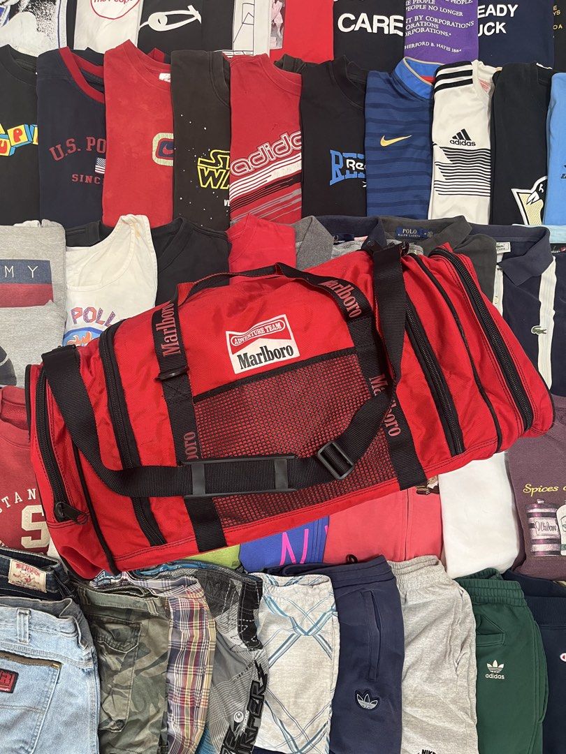 Red Marlboro Adventure Team Duffle Bag (Category: Sling Bags) located in Baao. Submitted by plainclothesdept (Listing ID 1464528039, Image 1). Description: Marlboro Duffle Bag height - 12 in. width - 12 in. length - 28 in. capacity - 66 liters signs of wear 2450 - Vintage Marlboro Adventure Team duffel bag - Bright red with black accents - Spacious main compartment - Side mesh pockets - Front zip pocket - Durable straps and handles - Ideal for tr