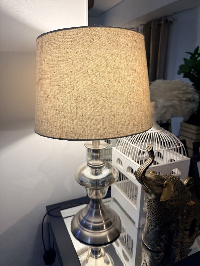 Silver and Glass Table Lamp with Beige Shade (Category: Lighting) located in Quezon City. Submitted by yourheaduhunter (Listing ID 1464472872, Image 3). Description: Beat price posted - Brushed silver base - Clear glass middle section - Textured beige linen shade - Ideal size for side table or nightstand - Provides a warm, inviting glow - In excellent working condition 54cm height 25-30cm shade diameter.