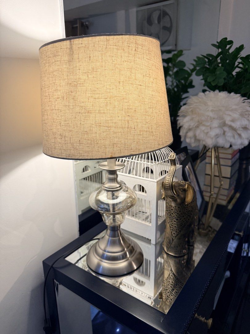 Silver and Glass Table Lamp with Beige Shade (Category: Lighting) located in Quezon City. Submitted by yourheaduhunter (Listing ID 1464472872, Image 1). Description: Beat price posted - Brushed silver base - Clear glass middle section - Textured beige linen shade - Ideal size for side table or nightstand - Provides a warm, inviting glow - In excellent working condition 54cm height 25-30cm shade diameter.