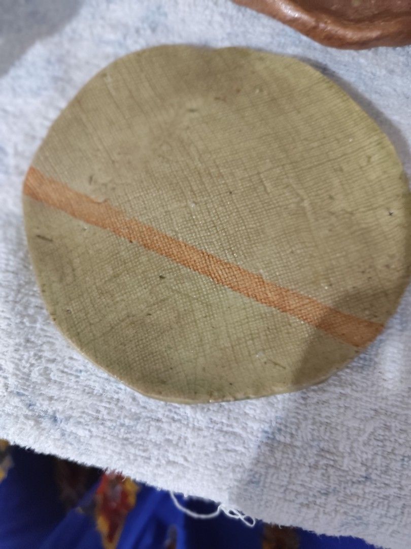 Small round ceramic plate with orange stripe detail (Category: Dinnerware & Cutlery) located in Manila. Submitted by marriage031073advocate (Listing ID 1464420086, Image 1). Description: - Small, round ceramic plate - Light green glaze with textured pattern - Features a single orange stripe - Ideal for displaying small trinkets - Can be used as a decorative coaster.