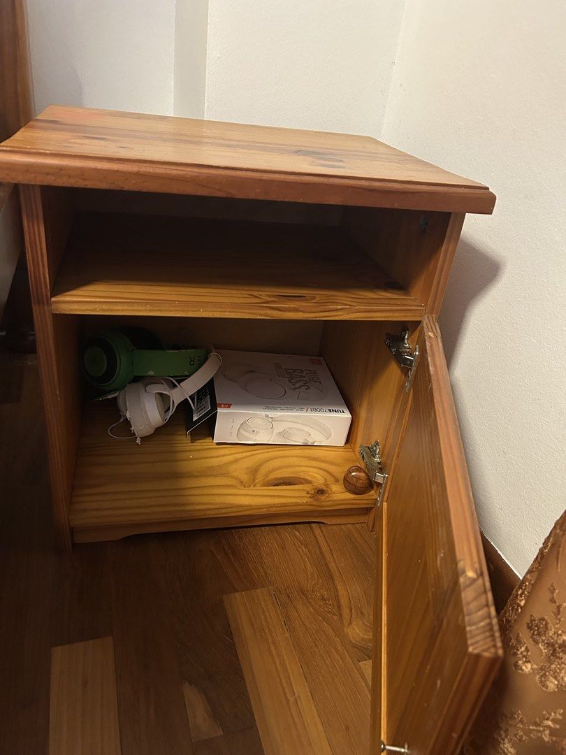 Solid pinewood Bedside table (Category: Shelves, Cabinets & Racks) located in Singapore. Submitted by kellysells (Listing ID 1464366317, Image 2). Description: Featuring a beautiful and prominent natural wood grain with a warm honey-brown finish. Two-Level Storage: Open Upper Shelf: A convenient, open cubby hole directly under the top surface, perfect for easy-access items. Enclosed Lower Cupboard: Below the shelf is a substantial storage cupboar