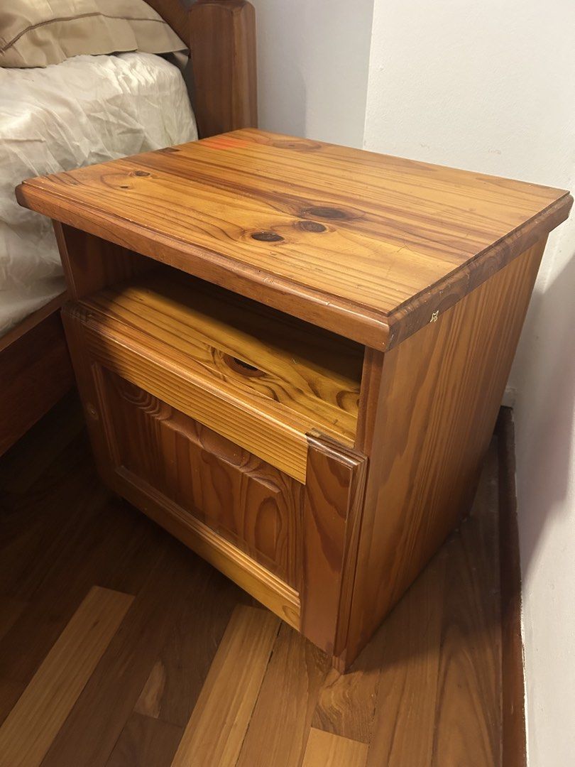 Solid pinewood Bedside table (Category: Shelves, Cabinets & Racks) located in Singapore. Submitted by kellysells (Listing ID 1464366317, Image 3). Description: Featuring a beautiful and prominent natural wood grain with a warm honey-brown finish. Two-Level Storage: Open Upper Shelf: A convenient, open cubby hole directly under the top surface, perfect for easy-access items. Enclosed Lower Cupboard: Below the shelf is a substantial storage cupboar