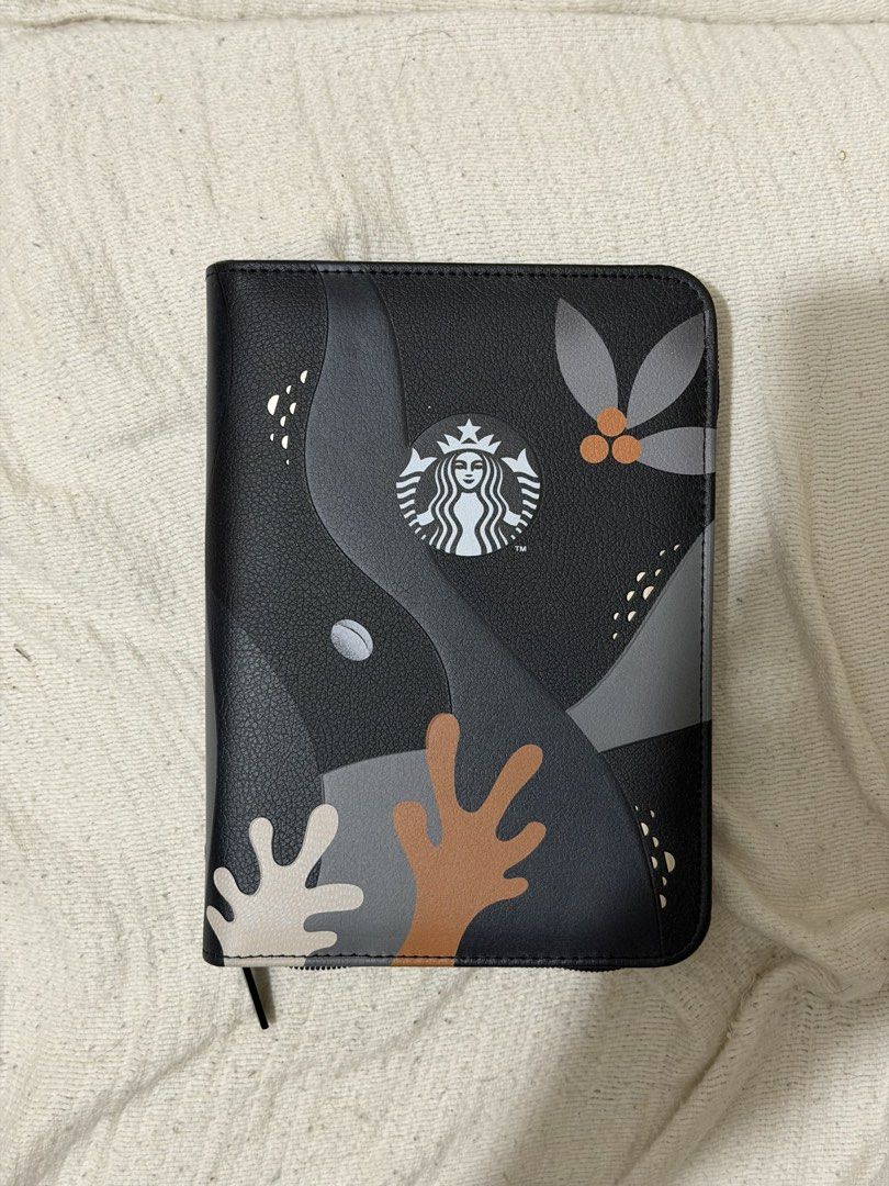 Starbucks Planner Cover with Pockets (Category: Stationery & School Supplies) located in Quezon City. Submitted by allthingspreloved.ph (Listing ID 1464556707, Image 1). Description: - Sleek black Starbucks planner cover - Features a cool abstract design - Iconic Starbucks logo on the front - Interior pockets for cards or notes - Secure zipper closure - Ideal for organizing your planner or travel documents.