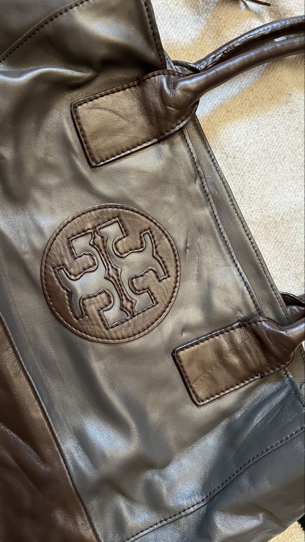 Tory Burch Leather Tote Bag (Category: Tote Bags) located in Cagayan de Oro. Submitted by nelsondel21723 (Listing ID 1464388596, Image 2). Description: - Authentic Tory Burch tote bag - Genuine leather in dark grey and brown - Iconic Tory Burch logo embossed on front - Bright blue interior lining - Interior zippered pocket and slip pocket - Magnetic snap closure - Spacious for essentials.