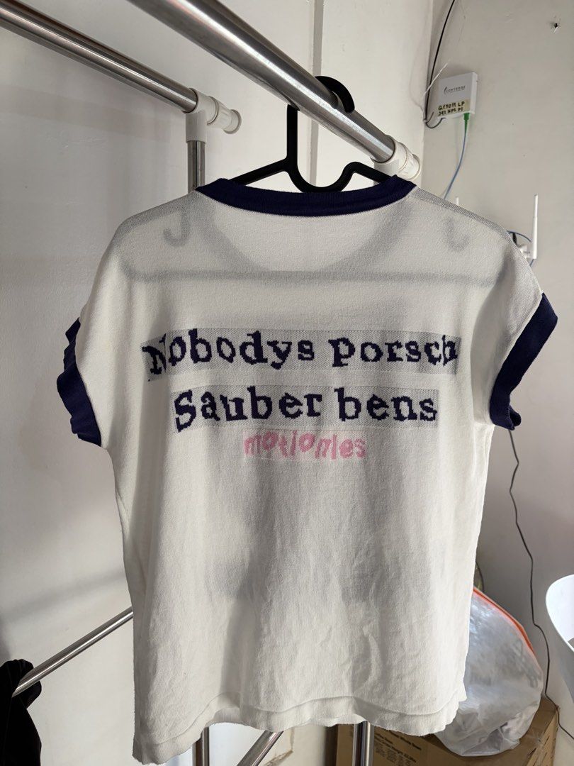 White T-shirt with Cat Graphic and Text (Category: Shirts) located in Quezon City. Submitted by daniclutter123 (Listing ID 1464453617, Image 2). Description: - White knit t-shirt with navy trim - Graphic cat face on the front with 'ASKMETO MAKΕYOU' text - Back features 'Nobodys porsch Sauber bens motionles' text - Short sleeves - Unique and eye-catching design.