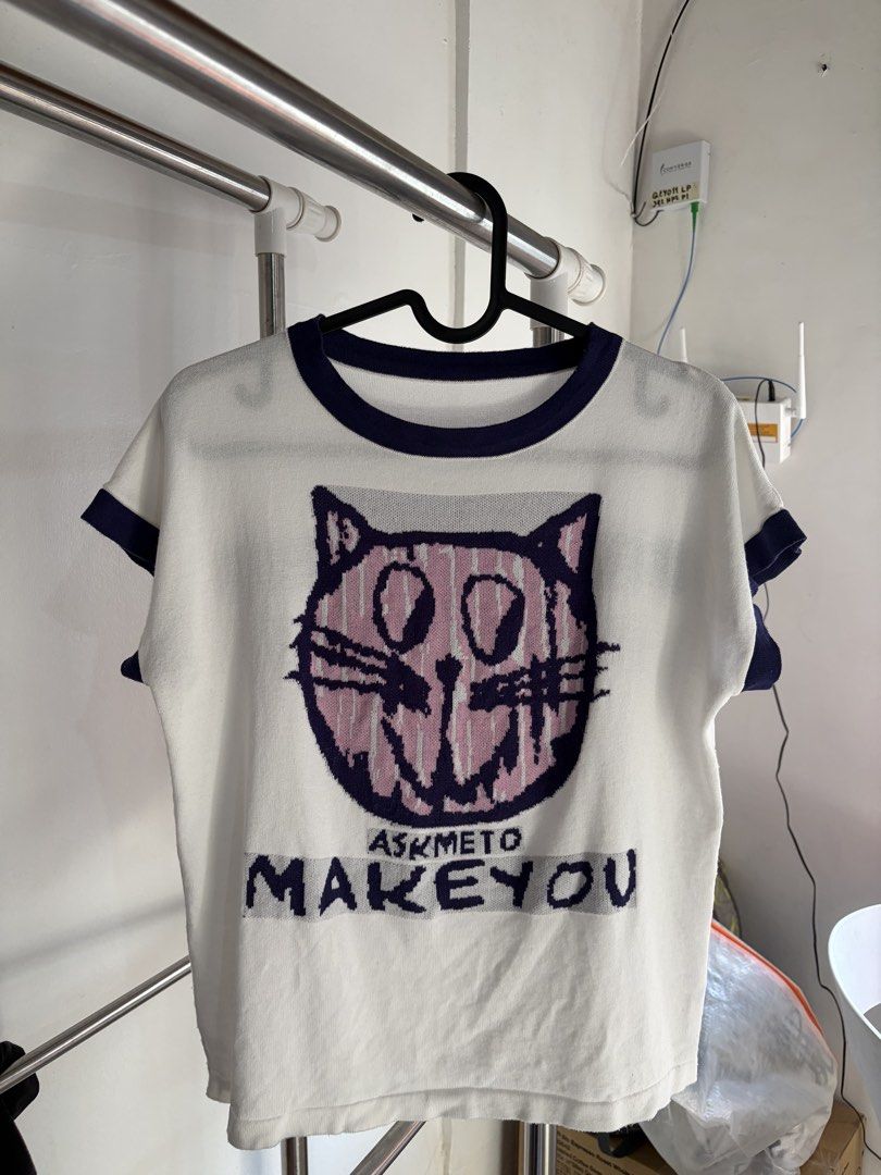 White T-shirt with Cat Graphic and Text (Category: Shirts) located in Quezon City. Submitted by daniclutter123 (Listing ID 1464453617, Image 1). Description: - White knit t-shirt with navy trim - Graphic cat face on the front with 'ASKMETO MAKΕYOU' text - Back features 'Nobodys porsch Sauber bens motionles' text - Short sleeves - Unique and eye-catching design.