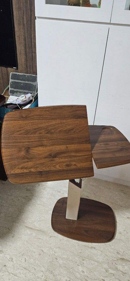 Versatile Adjustable Side Table (Category: Tables & Sets) located in Singapore. Submitted by ah_kher (Listing ID 1464472919, Image 3). Description: Versatile Adjustable Side Table • Suitable for use beside a sofa/couch or as a bedside table • 360° rotating tabletop for flexible positioning • One side of the tabletop can be tilted, allowing you to adjust the angle Suitable for use with laptops, books, meals, or other items while sitting on the sof