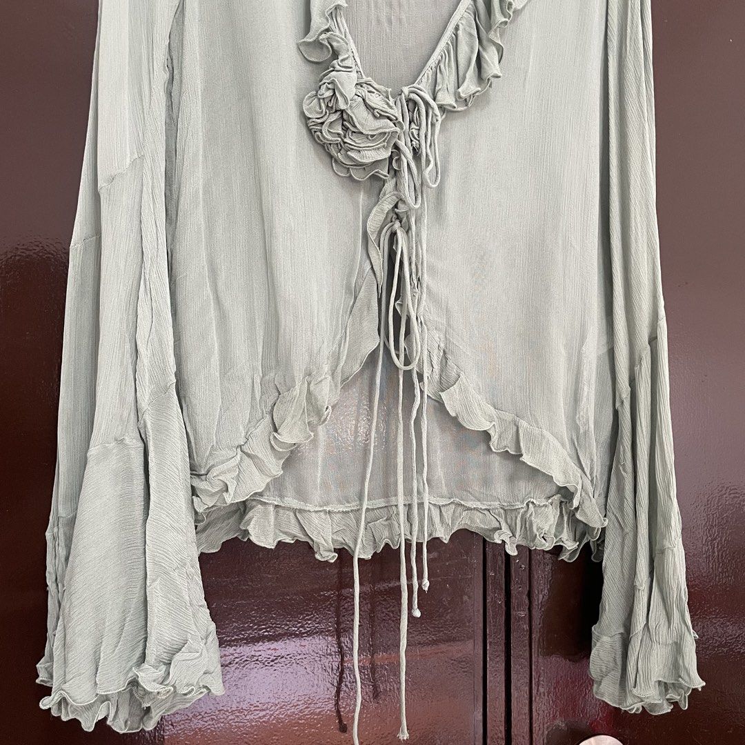 Zara Sheer Ruffle Tie Front Long Sleeve Blouse (Category: Longsleeves) located in Pasay City. Submitted by lovedbyzea (Listing ID 1464537513, Image 3). Description: - with minor flaw on the string (unnoticeable; please see photos) - Light green sheer blouse from Zara - Ruffled neckline and hem - Long bell sleeves - Tie front closure - Decorative floral detail at bust - Lightweight and flowy material - Perfect for layering or wearing alone.