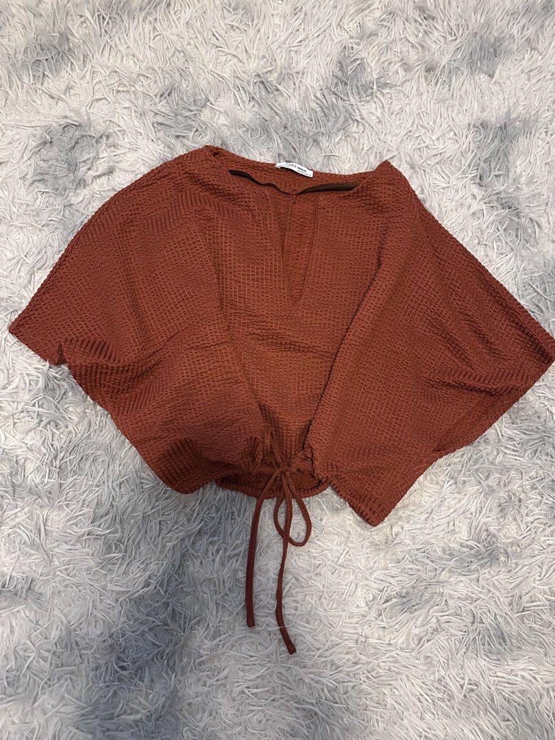 ZARA Textured Cropped Top with Drawstring (Category: Sleeveless) located in Batangas. Submitted by kulilayfinds (Listing ID 1464362342, Image 3). Description: - Rust-colored cropped top from ZARA - Textured waffle-like material - V-neck with a small slit - Adjustable drawstring at the hem - Short, dolman-style sleeves - Made in Turkey - Ideal for casual wear.