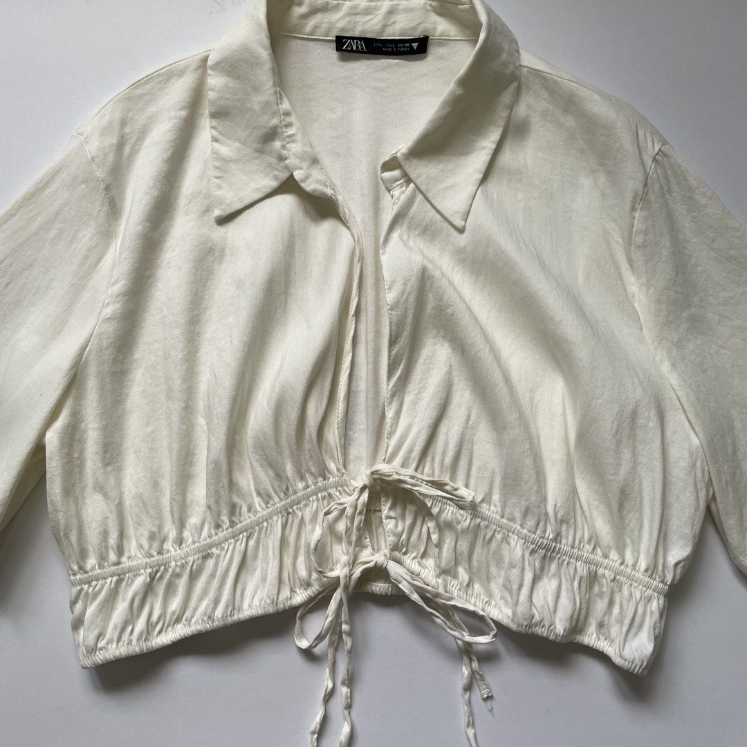 Zara White Cropped Shirt with Drawstring (Category: Shirts) located in Pasay City. Submitted by lovedbyzea (Listing ID 1464537007, Image 2). Description: - can fit Med to Large - White cropped shirt from Zara - Collared neckline and short sleeves - Drawstring detail at the hem to cinch the waist - Can be worn open or tied - Perfect for pairing with high-waisted bottoms - Easy to style for casual or dressed-up outfits.