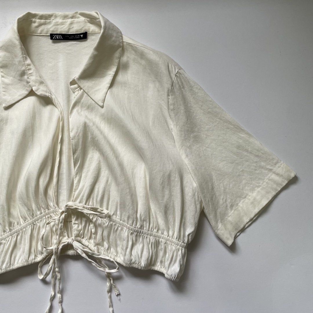 Zara White Cropped Shirt with Drawstring (Category: Shirts) located in Pasay City. Submitted by lovedbyzea (Listing ID 1464537007, Image 3). Description: - can fit Med to Large - White cropped shirt from Zara - Collared neckline and short sleeves - Drawstring detail at the hem to cinch the waist - Can be worn open or tied - Perfect for pairing with high-waisted bottoms - Easy to style for casual or dressed-up outfits.