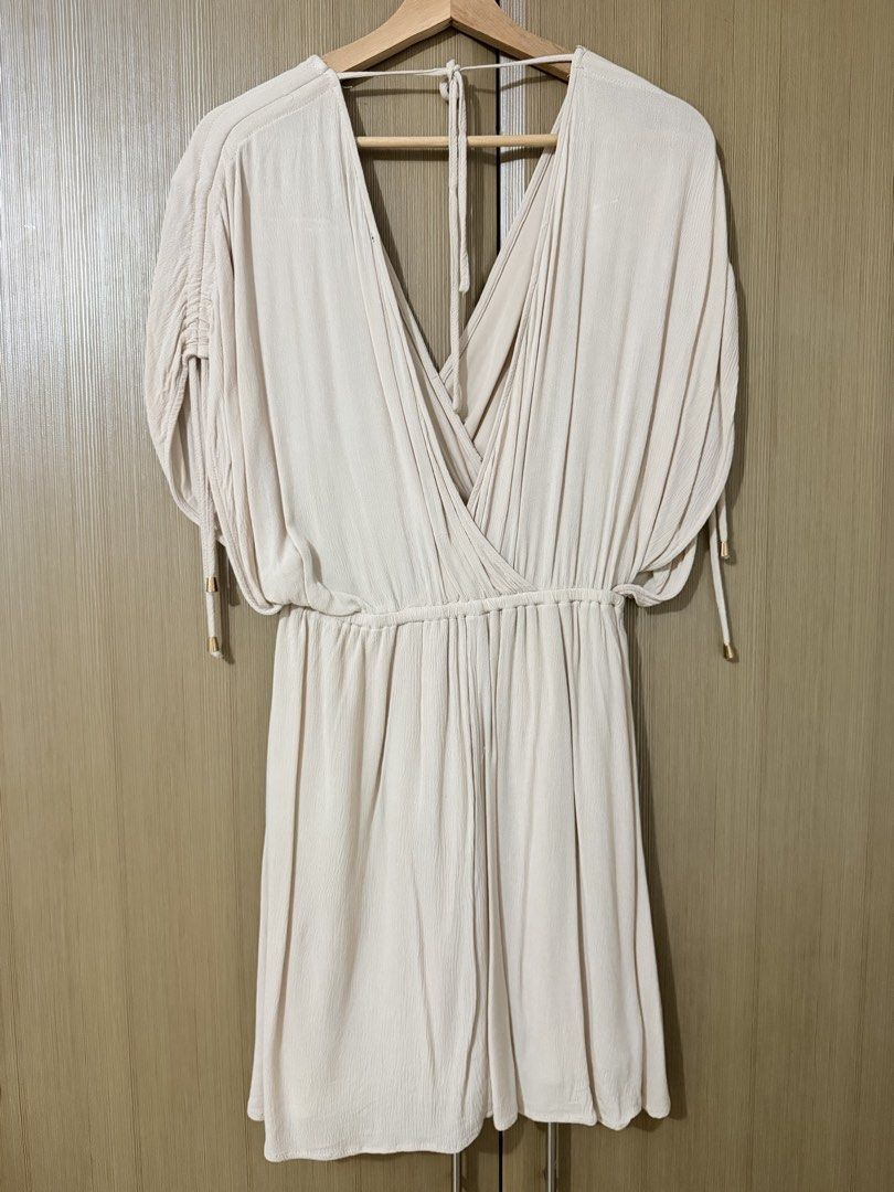 Aakaa Beige V-Neck Dress Size S (Category: Dresses) located in Manila. Submitted by mengxir20193848 (Listing ID 1464709869, Image 3). Description: - Brand: Aakaa - Size: S - Color: Beige - Style: V-neck wrap dress with ruched waist and shoulders - Sleeves: Short sleeves with metallic gold hardware accents on ties - Fabric: Soft, lightweight crinkle texture - Condition: Great for casual outings and warm weather Never used, 100% new.