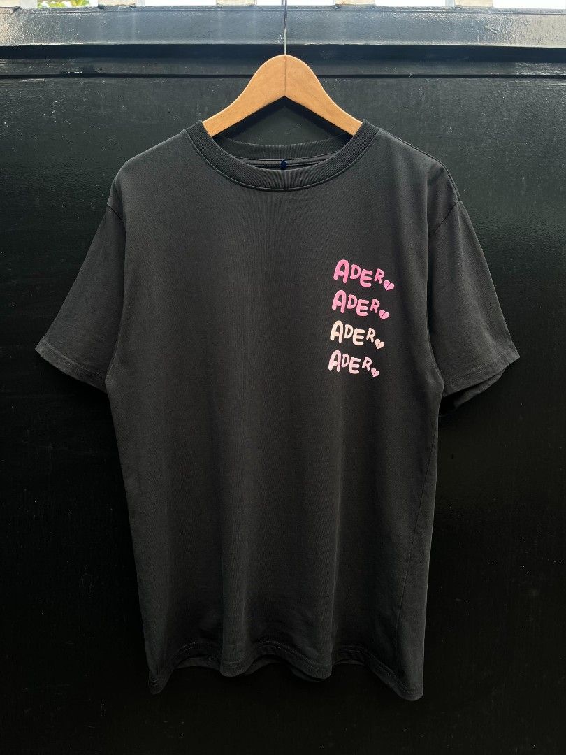 ADER Error (Category: Activewear) located in Manila. Submitted by lensandlove (Listing ID 1464618414, Image 1). Description: - Brand: ADER Error - Color: Black - Size: A1 - Collection: 2023 Fall Winter - Design: Pink repeated brand name with heart details on chest - Back: Plain - Style: Streetwear essential.