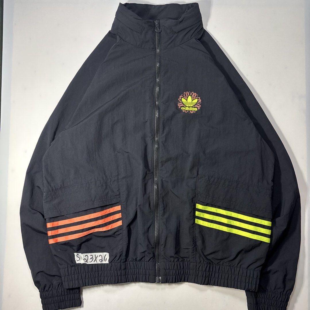 Adidas trefoil track / wind breaker jacket (Category: Coats, Jackets and Outerwear) located in Cavite. Submitted by sidirvinp76902 (Listing ID 1464748316, Image 1). Description: - Brand: Adidas - Color: Black with neon orange and yellow accents - Features: Packable hood, embroidered Trefoil logo on chest, large globe graphic with global text branding on the back - Pockets: Front pockets with vibrant striping - Closure & Fit: Full zip closure, ela