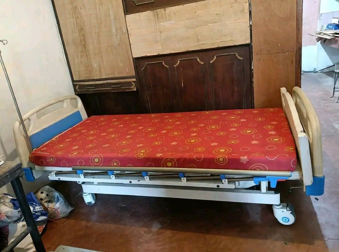 Adjustable Hospital Bed with Mattress and Side Rails (Category: Bed Frames & Mattresses) located in Mandaluyong City. Submitted by quickmountain.780662 (Listing ID 1464581449, Image 2). Description: - Adjustable hospital bed - Safety side rails included - Comes with a red patterned mattress - White and blue bed frame - Equipped with wheels for easy mobility - Features multiple adjustable sections - Suitable for home care or medical facilities - 3