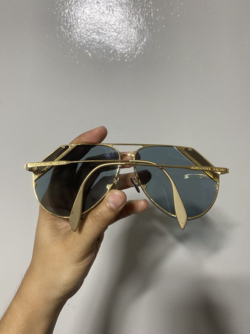 Alexander McQueen Gold Aviator Sunglasses (Category: Sunglasses & Eyewear) located in Pasacao. Submitted by wengpullar37205 (Listing ID 1464745434, Image 2). Description: - Brand: Alexander McQueen - Style: Aviator sunglasses with geometric brow bar - Frame: Gold-tone metal with crystal detailing on top corners - Lenses: Dark blue - Details: Brand name stamped on temples, adjustable nose pads included - Condition: Classic statement piece with min