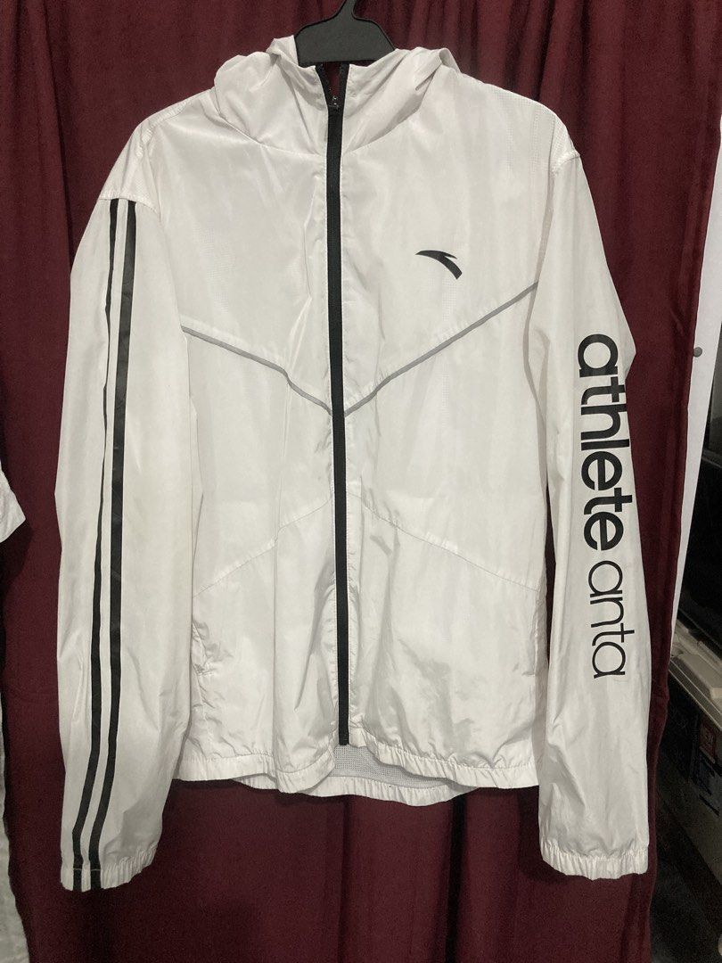 Anta Windbreaker Jacket XL (Category: Coats, Jackets and Outerwear) located in Manila. Submitted by burayagjho46288 (Listing ID 1464743272, Image 1). Description: - Brand: Anta Sports - Item: White windbreaker jacket - Size: XL (Tag: 180/96A) - Features: Full zip front, attached hood, lightweight material, inner mesh lining - Details: Black stripe on right sleeve, 'athlete anta' print on left sleeve - Ideal for: Running, workouts, and outdoor act