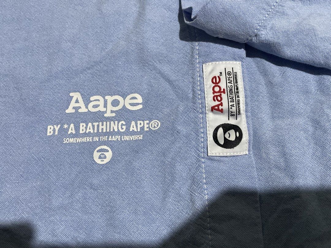 AUTHENTIC AAPE BY A BATHING APE Light Blue Button-Up Long Sleeve (Category: Tshirts & Polo Shirts ) located in Antipolo. Submitted by divineyyy69 (Listing ID 1464641885, Image 3). Description: - Light blue button-up shirt from AAPE BY A BATHING APE - Vertical brand name print on front placket - Small chest pocket with camo detail tag - Classic button-down collar - Long sleeves with button cuffs - Versatile for casual and smart-casual outfits -l:2