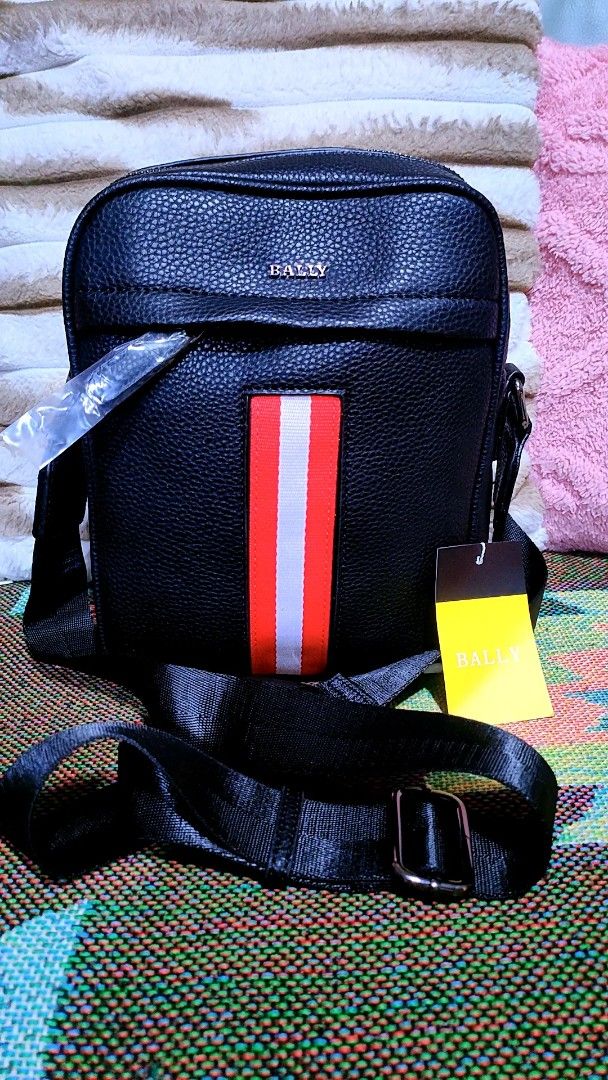 Bally Black Messenger Bag with Red Stripe (Category: Sling Bags) located in Baliuag. Submitted by marieannfernando23 (Listing ID 1464690475, Image 1). Description: - Authentic black pebble-textured leather crossbody bag - Features iconic red and white vertical stripe with silver Bally logo - Includes adjustable black shoulder strap - Secure main zippered compartment with inner zip pocket and fabric lining - Comes with yellow brand tag attached - 