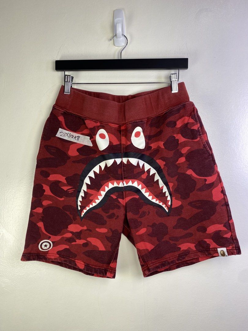 BAPE Red Camo Shark Shorts (Category: Shorts) located in Manila. Submitted by declutterpromax (Listing ID 1464601139, Image 1). Description: - BAPE red camouflage shorts - Iconic shark graphic on the front - Includes APE HEAD logo and WGM graphic - Comfortable sweatshort material - Elastic waistband for a perfect fit.