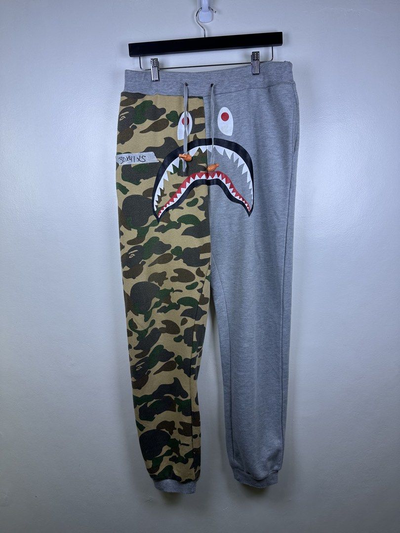 BAPE Shark Split Camo Sweatpants (Category: Joggers) located in Manila. Submitted by declutterpromax (Listing ID 1464617991, Image 1). Description: - BAPE Sweatpants - Iconic Shark Graphic Design - Half Camo, Half Grey Colorway - Size: XS - Features Drawstring Waist - Perfect for streetwear enthusiasts.