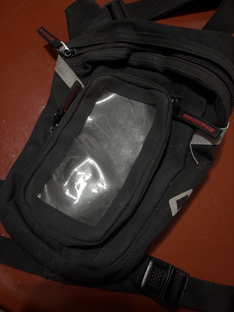 Black Motorcycle Drop Leg Bag with Phone Pouch (Category: Belt bags, Clutches and Pouches) located in Manila. Submitted by finderskeepersmnl_092026 (Listing ID 1464720253, Image 2). Description: - Durable tactical drop leg bag with adjustable straps and quick-release buckles - Clear plastic touch screen window on the front flap for easy smartphone access - Multiple zippered compartments to keep your essentials organized - Reflective stripes for a