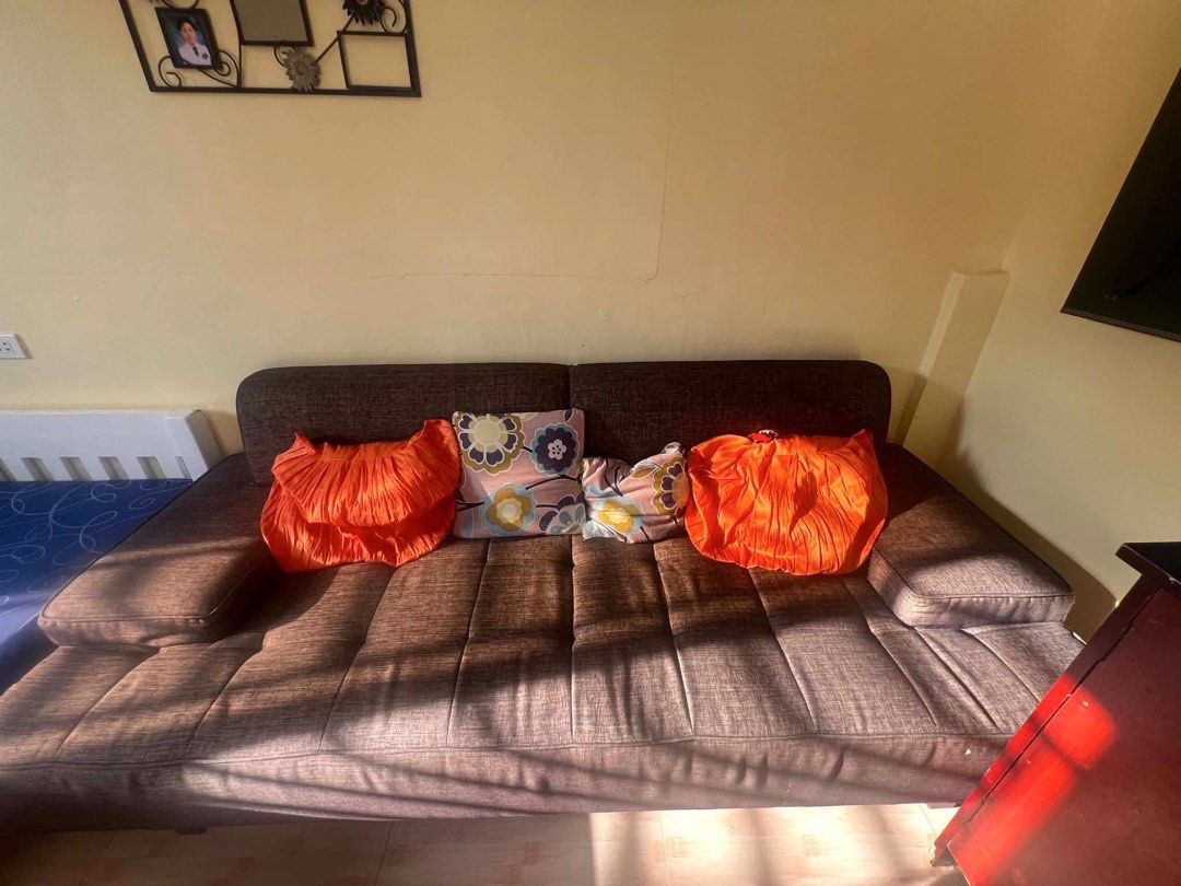Brown Tufted Sofa (Category: Sofas) located in Cainta. Submitted by rominaamor (Listing ID 1464586863, Image 1). Description: - Comfortable brown sofa with classic tufted seat and armrests. - Includes two vibrant orange pleated accent pillows. - Ideal for living rooms or guest rooms. - Offers ample space for lounging and relaxation. - Photo shows sofa with natural sunlight..