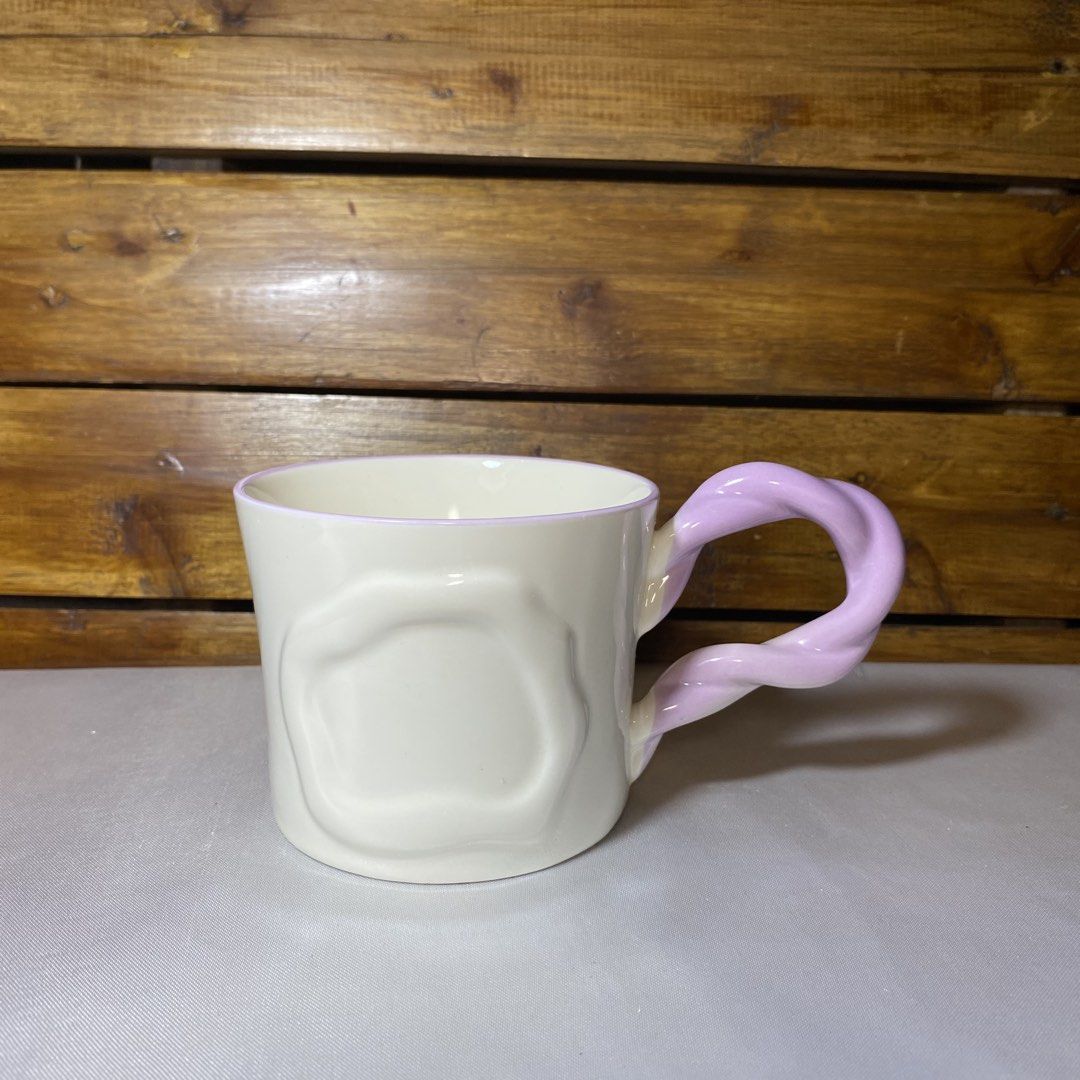 Ceramic Mug with Twisted Handle (Category: Coffee & Tea Tableware) located in Quezon City. Submitted by oliviararo46032 (Listing ID 1464670480, Image 1). Description: - Cream-colored mug with a unique wavy texture. - Features a fun, twisted pastel purple handle. - Subtle light purple trim around the rim. - Ideal for your morning coffee or tea. - Adds a playful touch to your kitchenware..