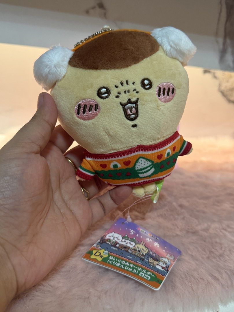 Chiikawa Kurimanju Plush Keychain (Category: Plushies & Soft Toys) located in Quezon City. Submitted by parischanelcollection (Listing ID 1464749269, Image 1). Description: - Item: Kurimanju Plush Keychain - Origin: Chiikawa x Seven-Eleven Japan Lottery (D Prize) - Details: Wears a festive winter sweater with onigiri and red heart patterns - Condition: Brand new with tag still attached - Material: Soft plush with brown and white details - Perfect