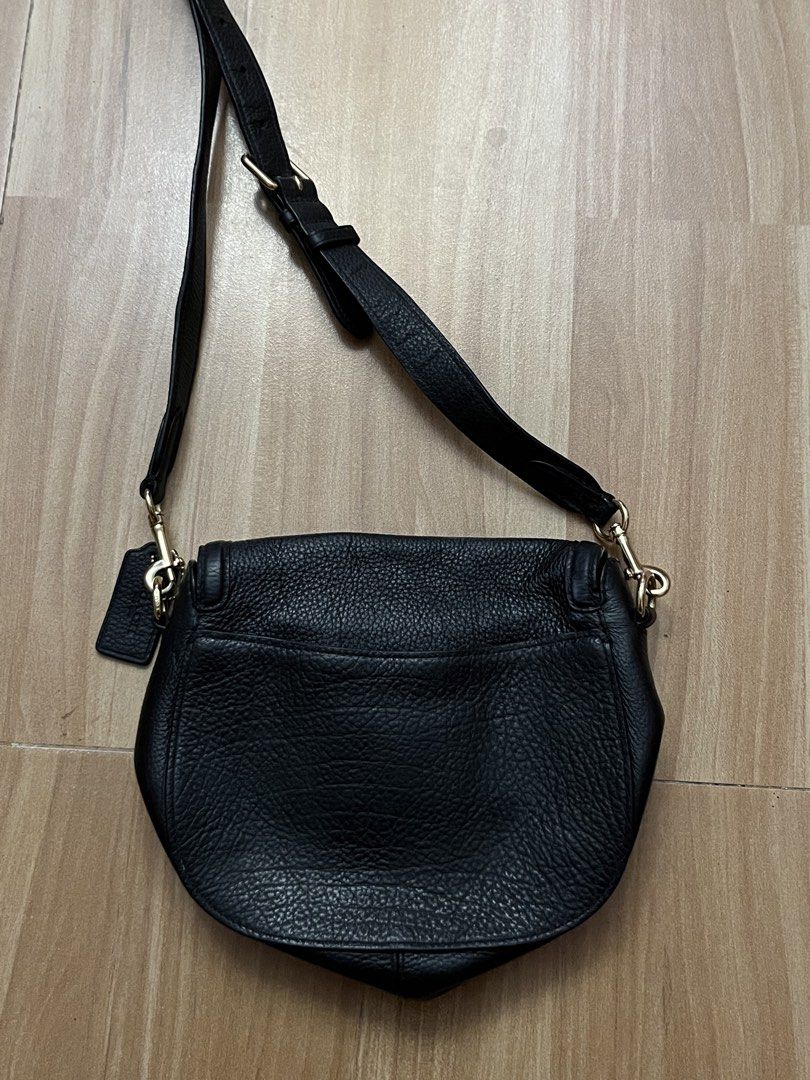Coach Black Leather Saddle Crossbody Bag (Category: Luxury Bags & Wallets) located in Victorias. Submitted by lan1877 (Listing ID 1464708545, Image 3). Description: - Brand: Coach - Material: Premium black pebble leather - Hardware: Gold-tone horse and carriage closure - Strap: Adjustable with buckle - Exterior: Convenient back slip pocket and removable leather hangtag - Interior: Black fabric lining with zip and slip pockets - Condition: Clean s