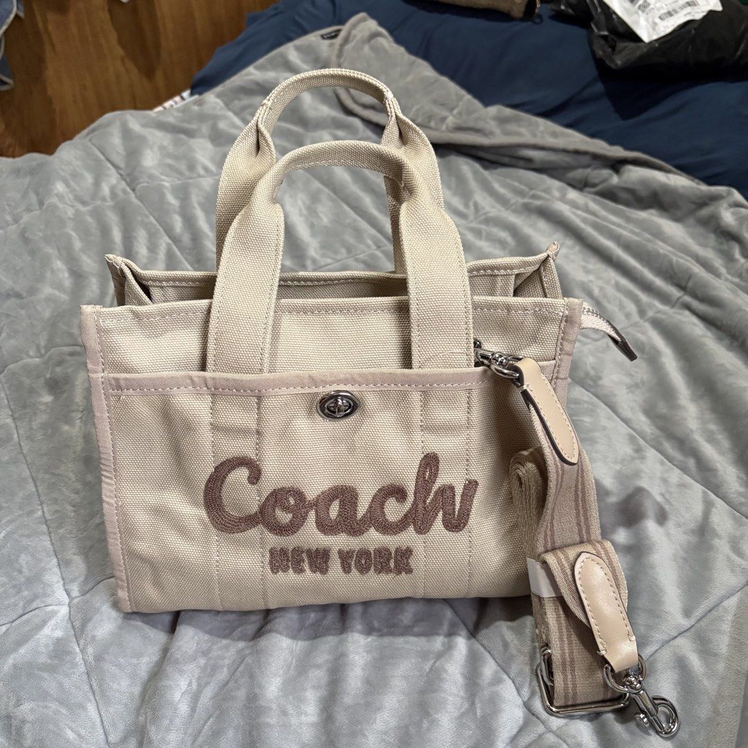 Coach New York Canvas Tote Bag with Strap (Category: Tote Bags) located in Carmen. Submitted by rr_thrifts (Listing ID 1464719785, Image 1). Description: - Brand: Coach New York - Color/Material: Beige canvas with embroidered front lettering - Versatile carry: Includes sturdy top handles and a matching adjustable shoulder strap - Secure closure: Zip-top main compartment with Coach-branded hardware - Pockets: Exterior slip pocket with turnlock clo
