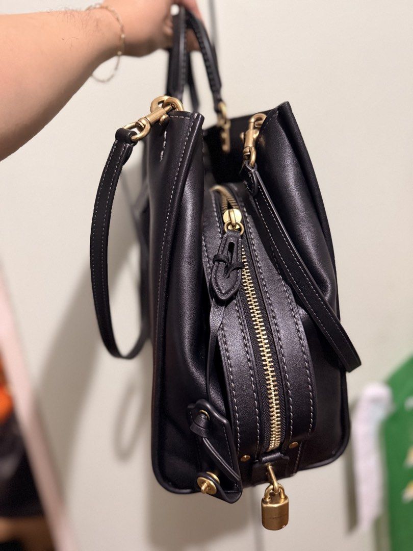 Coach Rogue Black Leather Tote Bag (Category: Luxury Bags & Wallets) located in San Juan City. Submitted by zenrabbit.6105c7 (Listing ID 1464691379, Image 2). Description: - Brand: Coach Rogue Bag - Color/Material: Classic black leather with brass hardware - Carry options: Top handles and detachable shoulder strap - Compartments: Structured sides with secure zippered compartments - Condition: Clean inside and out, solid construction - Extras: Sig