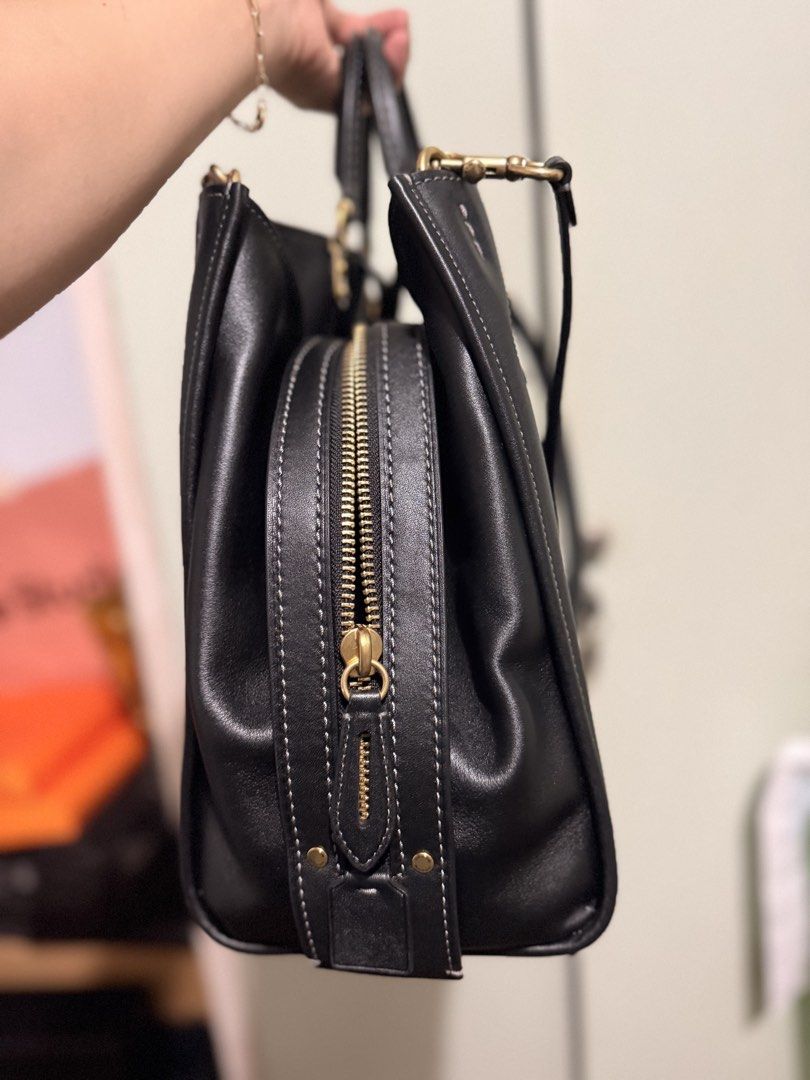 Coach Rogue Black Leather Tote Bag (Category: Luxury Bags & Wallets) located in San Juan City. Submitted by zenrabbit.6105c7 (Listing ID 1464691379, Image 3). Description: - Brand: Coach Rogue Bag - Color/Material: Classic black leather with brass hardware - Carry options: Top handles and detachable shoulder strap - Compartments: Structured sides with secure zippered compartments - Condition: Clean inside and out, solid construction - Extras: Sig