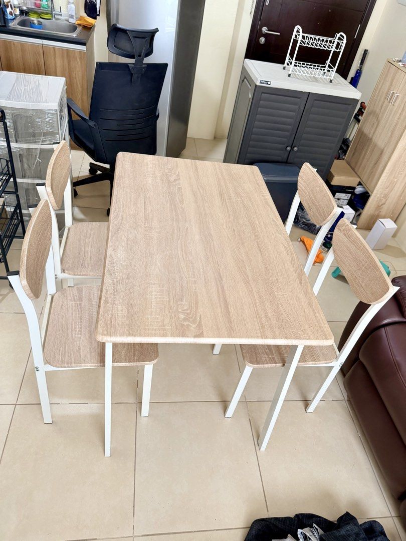 Compact Dining Table and 4 Chairs Set (Category: Tables & Sets) located in Makati City. Submitted by viajero_republic (Listing ID 1464602984, Image 2). Description: - Includes 1 dining table and 4 chairs. - Table features a wood-look tabletop with white metal legs. - Chairs have white metal frames with matching wood-look seat panels. - Ideal for small apartments or dining areas. - Easy to wipe clean for hassle-free maintenance. - Chairs tuck neat