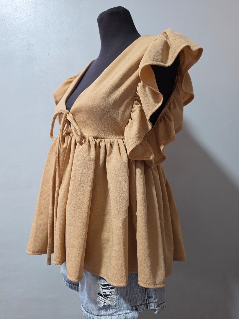 Cute Beige Ruffle Wrap Top with Tie Detail medium (Category: Blouses) located in Paranaque City. Submitted by franinnashop (Listing ID 1464639454, Image 2). Description: - Chic beige top - Ruffled sleeves and neckline - Adjustable front tie for a cinched waist - Flowy, gathered hem - Versatile for pairing with jeans or shorts - Comfortable and stylish for casual outings declutter medium to large paranque city.