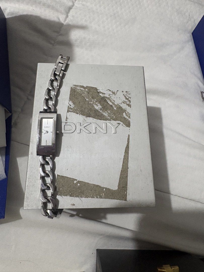 DKNY silver rectangular chain bracelet watch with original box (Category: Women's Watches) located in Manila. Submitted by nykji96 (Listing ID 1464692670, Image 1). Description: - Brand: DKNY - Style: Silver-tone wristwatch with rectangular dial and chain-link bracelet - Dial: Clean white face with minimal markers - Inclusion: Original DKNY branded cardboard box (note: noticeable wear and peeling on the cover) - Condition: Battery status unknown,