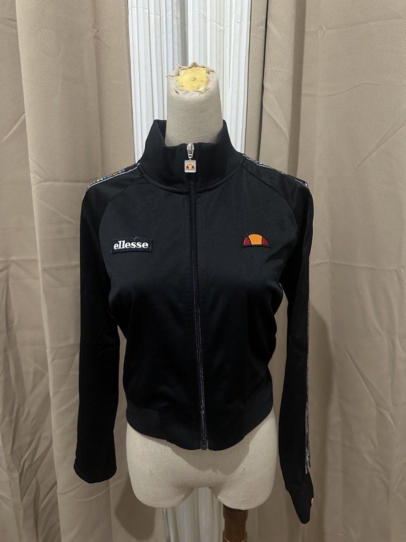 Ellesse Black Track Jacket with Logo (Category: Coats, Jackets and Outerwear) located in Taguig. Submitted by kmhosseini90202 (Listing ID 1464685369, Image 1). Description: - Black Ellesse track jacket - Ellesse logo on chest and sleeve - Full zip front - Stand-up collar - Patterned stripe detail on sleeves - Ideal for casual wear or sports.