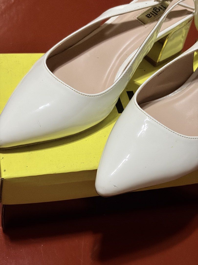 Figlia Tristan White Pumps Size 39 (Category: Heels) located in Manila. Submitted by finderskeepersmnl_092026 (Listing ID 1464708777, Image 3). Description: - Brand/Model: Figlia Tristan Pumps - Color: White with elegant gold-tone trim - Size: 39 - Style: Pointed toe, slingback strap, adjustable buckle closure, and chunky low heel - Comfort: Nude cushioned insoles with gold branding - Inclusions: Comes with original SM Store box - Condition: Exce