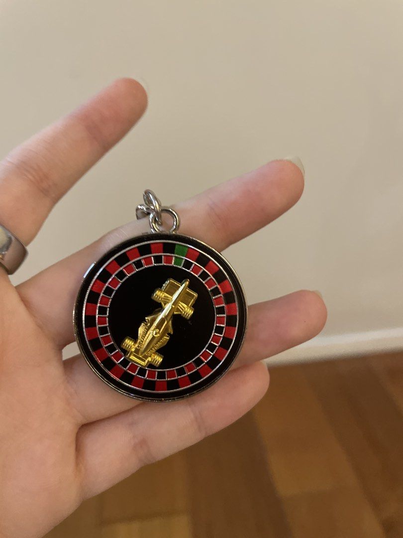 Futuro Pilot Monaco F1 Roulette Wheel Keychain (Category: Vehicle & Diecast Models) located in Mandaluyong City. Submitted by beautyfashdeclutter (Listing ID 1464722516, Image 2). Description: - Official Futuro Pilot Monaco merchandise - Circular roulette wheel pendant with a gold race car figurine in the center - Reverse side features an authentic Monaco Monte-Carlo stamp - Silver hardware complete with chain and split ring - Brand new, comes wi