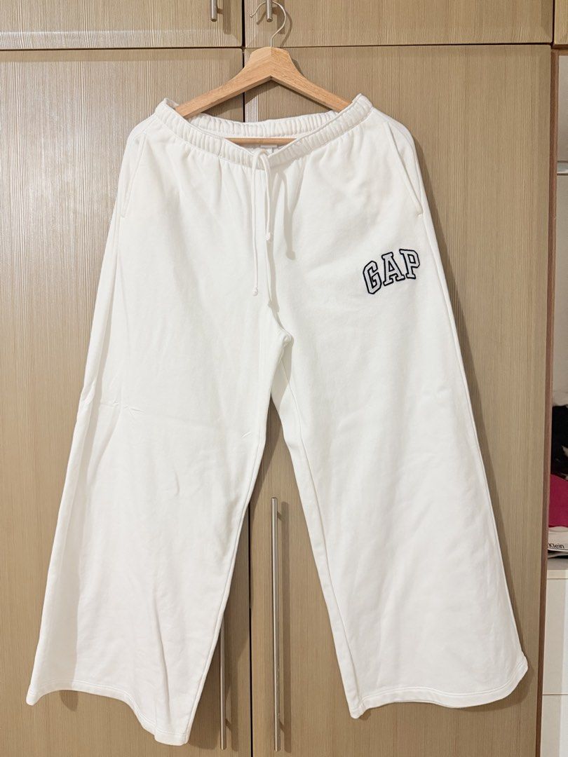 GAP White Wide Leg Sweatpants (Category: Joggers) located in Manila. Submitted by mengxir20193848 (Listing ID 1464707070, Image 1). Description: - Color: White - Style: Wide leg cut - Material: Soft fleece for ultimate comfort - Details: Elastic waistband, adjustable drawstring, and contrasting black embroidered GAP logo on the left leg - Condition: Brand new / Excellent (as good as new) - Perfect for: Lounging or casual streetwear outfits - Mode
