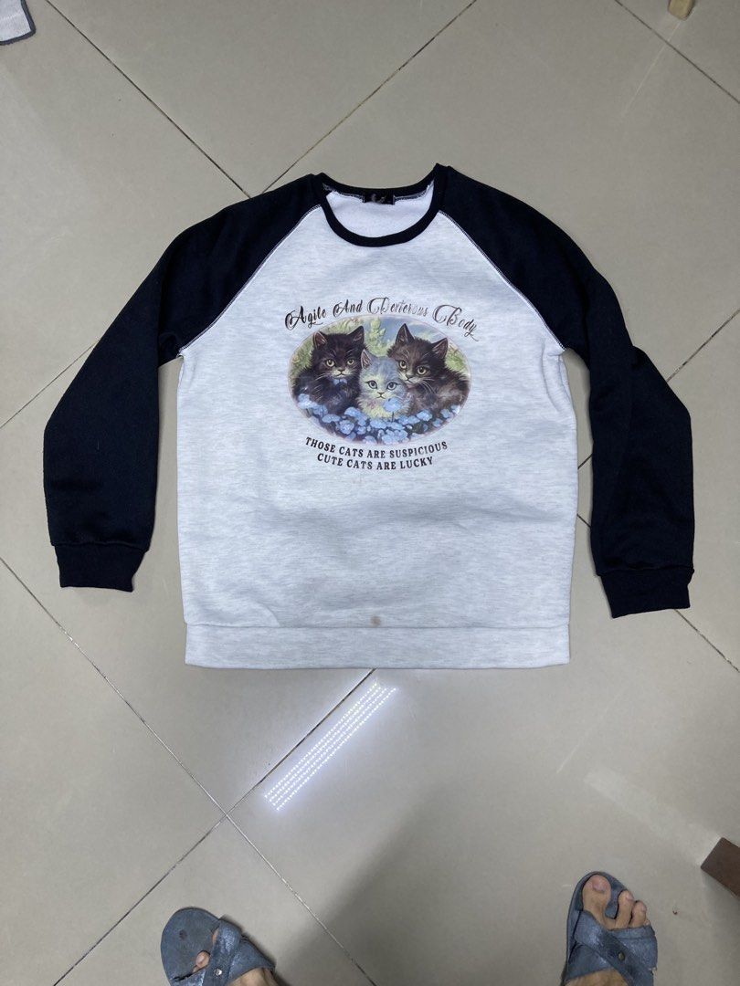Grey Raglan Sleeve Sweatshirt with Cat Print (Category: Longsleeves) located in Bulacan. Submitted by fordypao (Listing ID 1464593579, Image 1). Description: - Grey sweatshirt with black raglan sleeves. - Features a cute print of three cats. - Small stain on the front, as shown in the last photo. - Tag is slightly visible..