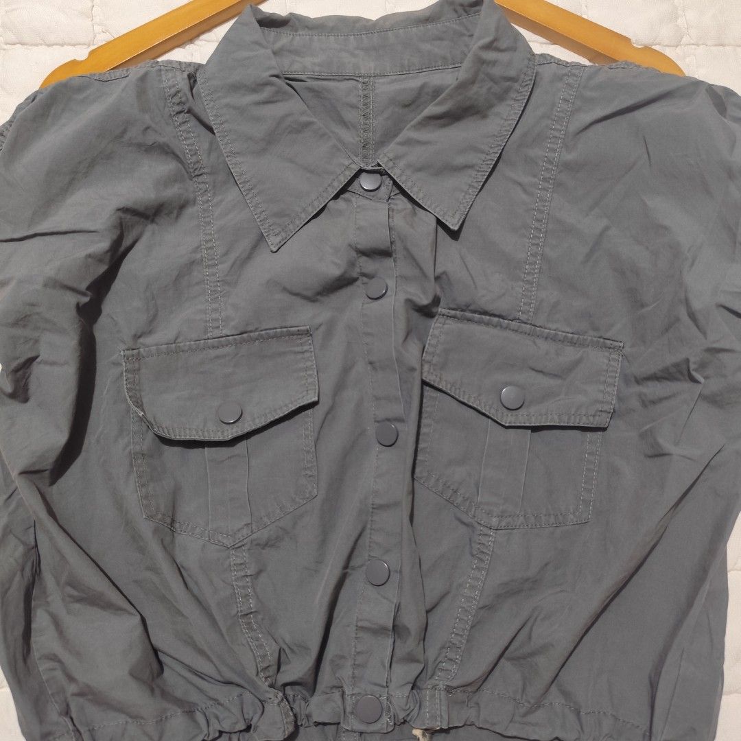 Grey utility crop top with dual chest pockets and drawstring hem (Category: Sleeveless) located in Bacolod City. Submitted by dearicawho.56 (Listing ID 1464709840, Image 2). Description: - Color: Dark grey - Style: Utility crop top with classic shirt collar - Closure: Front snap buttons - Pockets: Two chest pockets (design only, not working pockets) with flap covers - Fit: Adjustable drawstring hem to cinch the waist 🧾Mode of payment: 💙Gcash 💚