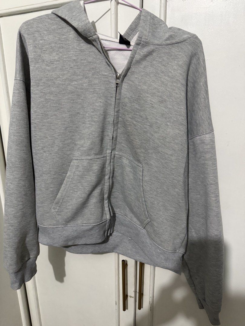 Grey Zip-Up Hoodie (Category: Coats, Jackets and Outerwear) located in Manila. Submitted by lenaraedeech (Listing ID 1464679145, Image 1). Description: - Grey zip-up hoodie - Features a front pocket - Includes a hood - Basic and comfortable design - Ideal for layering or wearing solo - Versatile for any outfit - Great for casual occasions.