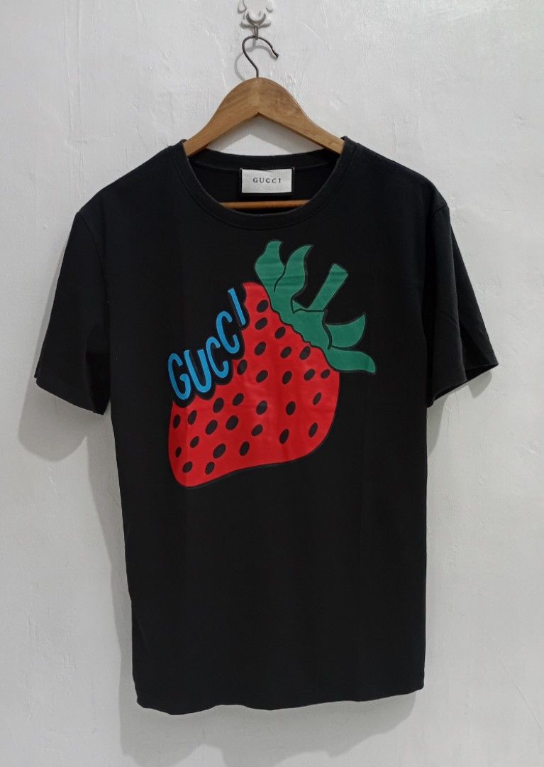 Gucci🍓 🖤TeeShirt (Category: Luxury Apparel) located in Navotas City. Submitted by ms.soulana (Listing ID 1464693483, Image 1). Description: PreOwned Lightly Used Gucci Strwberry Printed black TeeShirt -Medium - Color: Black - Design: Large red strawberry graphic with green stem and blue Gucci logo lettering - Fit: Standard fit - Details: Crew neckline, short sleeves, solid black back - Condition: Clean and well-maintained - Style: Casual design