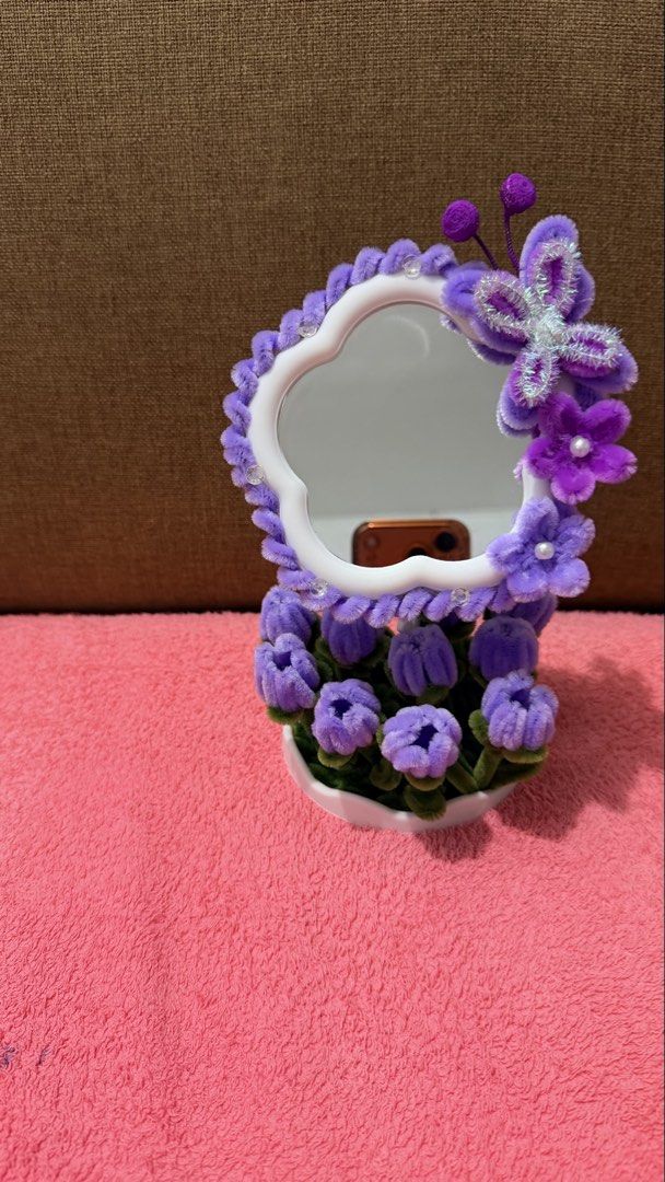 Handmade Pipe Cleaner Flower Desk Mirror (Category: Mirrors) located in Dasmarinas. Submitted by ligean2738954 (Listing ID 1464724886, Image 2). Description: Custom handmade vanity mirror decorated with fluffy pipe cleaner flowers and butterfly accents. Available in two colorways: purple or pink and red. Stands securely in a white scalloped base. Cute decor piece for a vanity table, desk, or bedside table. Bright and cheerful room accessory..